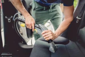 Details Of Car detailing, Male Using Professional Steam Vacuum on car seats.