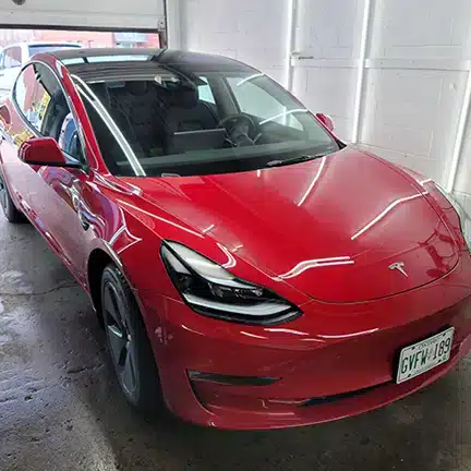 Red Tesla Model 3 after professional ceramic coating at MNV Auto Detailing in Toronto, showcasing exceptional gloss, deep colour and a highly reflective finish
